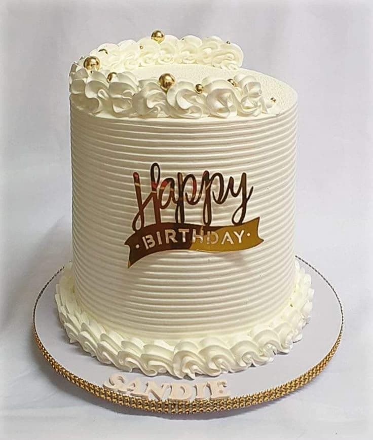 An elegant cream cake finished with piped buttercream and gold beads