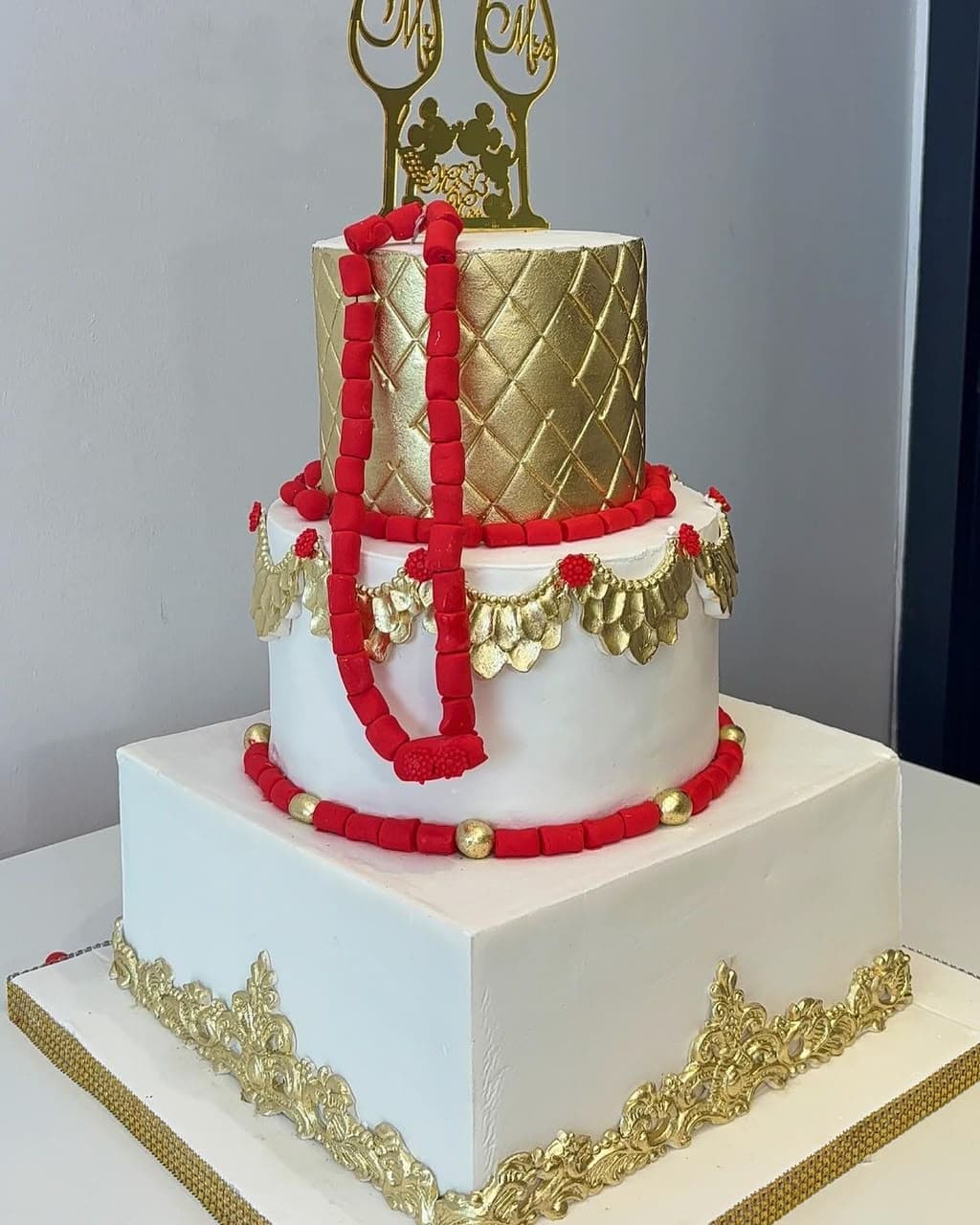 A traditional wedding cake finished in gold with red coral beading