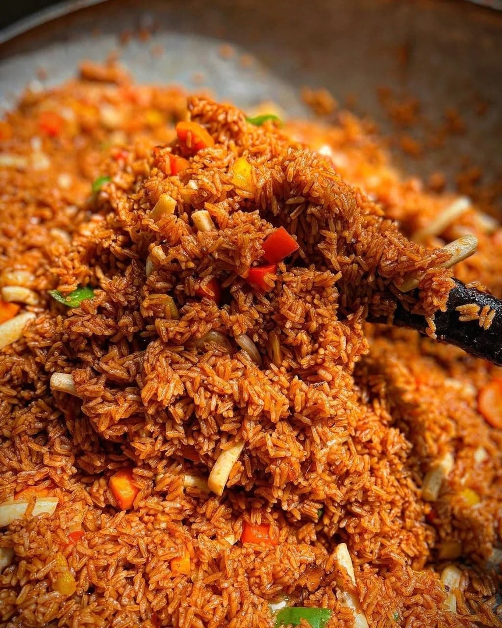 Jollof rice being stirred in a large pot