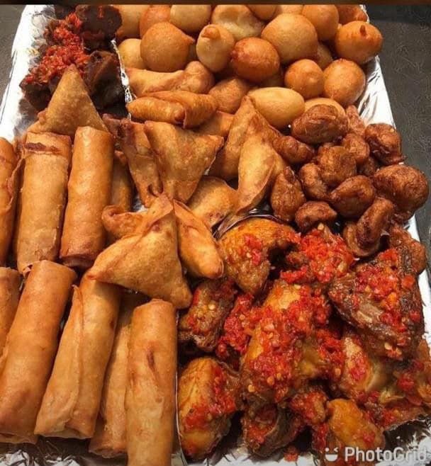 A tray of puff puff, spring rolls, samosas and peppered chicken wings